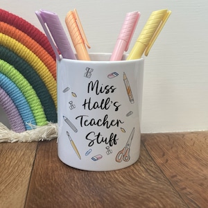 May include: White ceramic pencil holder with the text "Miss Hall's Teacher Stuff" and a variety of school supplies printed on it. The holder has four pastel coloured pens inside.