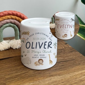 Könnte beinhalten: Zwei weiße Keramik-Sparschweine mit Dschungeltier-Motiv. Eine Box sagt "On your christening day Oliver 30.04.2024 St Mary's Church Love from Auntie Sophie" und die andere sagt "On your baptism day Evelyn 30.04.2024 St Mary's Church".