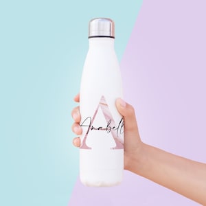 May include: White reusable water bottle with a pink and gold marble design and the name "Anabell" written in black script inside a triangle.