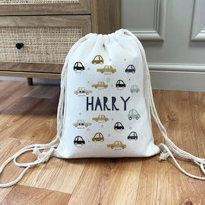 May include: A white canvas drawstring bag with a blue and gold car pattern and the name "HARRY" printed in black.