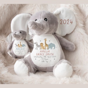 May include: A gray plush elephant stuffed animal with a white patch on its chest. The patch has a design of a zebra, lion, giraffe, and elephant. The text on the patch reads "Amelia Grace Smith, Wednesday 18th April 2024, 15.44pm, 6lbs 7oz". The elephant's ear has a pink patch with the text "2024".