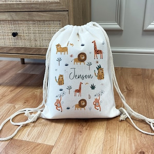 May include: A white drawstring bag with a jungle animal print. The bag features lions, tigers, giraffes, and monkeys. The name "Jenson" is printed on the bag.