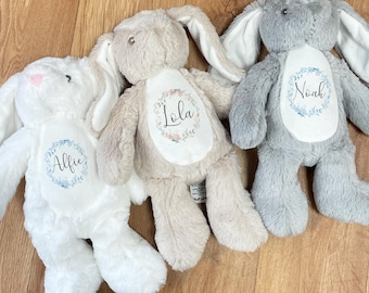May include: Three plush bunny toys with embroidered floral wreaths and personalized names: Alfie, Lola, and Noah. The bunnies are white, beige, and gray.