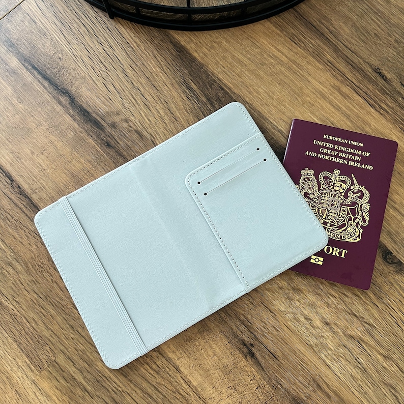 May include: A light blue passport holder with a pocket for a passport or credit card. The holder is lying on a wooden surface next to a burgundy passport.