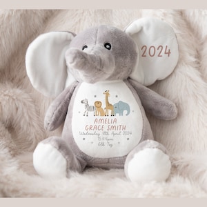 May include: Gray plush elephant stuffed animal with a white patch on its chest. The patch has a design of a zebra, lion, giraffe, and elephant with stars. The text on the patch reads "Amelia Grace Smith, Wednesday 18th April 2024, 15.44pm, 6lb 7oz". The elephant's ear has the text "2024" in pink.