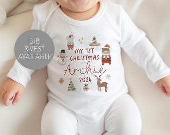 May include: White baby onesie with a red and brown Christmas design. The onesie says "My 1st Christmas Archie 2024" and features a snowman, a reindeer, a bear, a Christmas tree, and a snow globe.