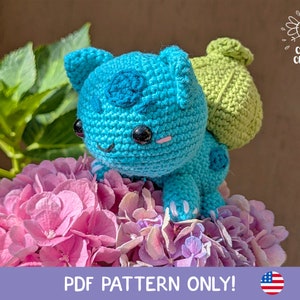 Puede incluir: Patrón de crochet para un juguete amigurumi azul y verde. El juguete está sentado en una flor rosa y morada. El patrón está disponible para descargar en PDF.  PDF PATTERN ONLY!