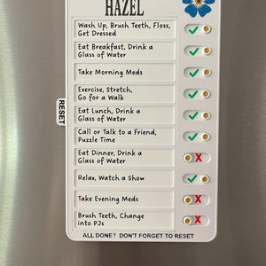 May include: A white magnetic daily checklist with the text "FORGET-ME-NOT HAZEL". The checklist includes tasks like "Wash Up, Brush Teeth, Floss, Get Dressed" and "Eat Breakfast, Drink a Glass of Water". A blue flower graphic is in the upper right corner.