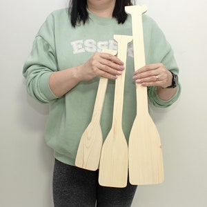 Peut inclure: Trois formes de pagaies en bois de différentes tailles. Les pagaies sont non finies et ont une couleur bois naturelle.