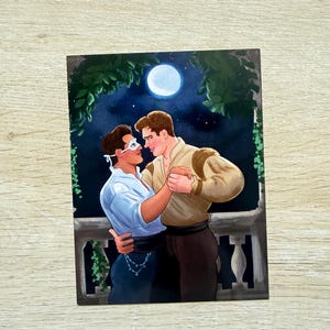 May include: A romantic illustration depicts a couple dancing under a full moon. The man wears a tan shirt and dark pants, while the other person wears a white shirt, a mask, and dark pants. Green foliage frames the scene.