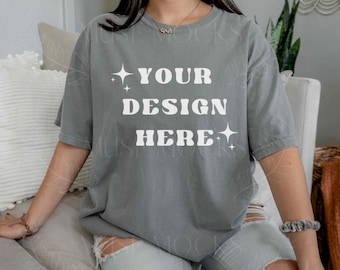 May include: A woman wearing a gray oversized t-shirt with the text "YOUR DESIGN HERE" in white. The shirt has a distressed look and is perfect for customizing with your own design.