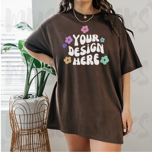 May include: A brown oversized t-shirt with a white graphic that says "YOUR DESIGN HERE" surrounded by colorful flowers.