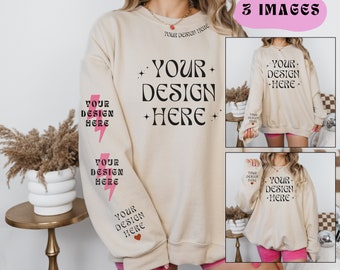 May include: A beige sweatshirt with the text "YOUR DESIGN HERE" in black lettering. The sweatshirt has pink lightning bolts on the sleeves and a pink heart on the left sleeve. The sweatshirt is being modeled by a person.
