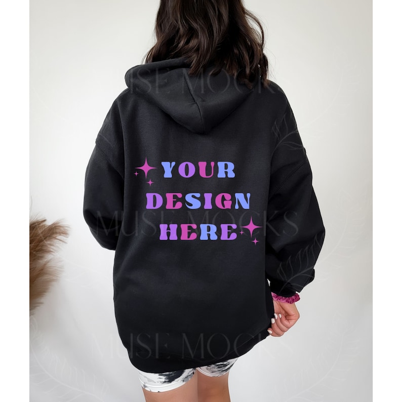 Pu&ograve; includere: Felpa con cappuccio nera con il testo "YOUR DESIGN HERE" in lettere rosa, blu e viola con stelle su entrambi i lati.