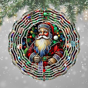 May include: A round Christmas ornament featuring Santa Claus in a stained-glass style design. Santa is wearing a red suit and hat, with a long white beard and blue gloves. The ornament has a decorative border with green, red, and white accents.
