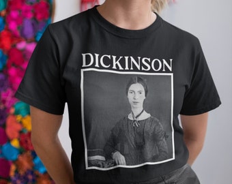 Può includere: Una maglietta nera con una grafica bianca di un ritratto di Emily Dickinson e il testo "Dickinson" sopra il ritratto.