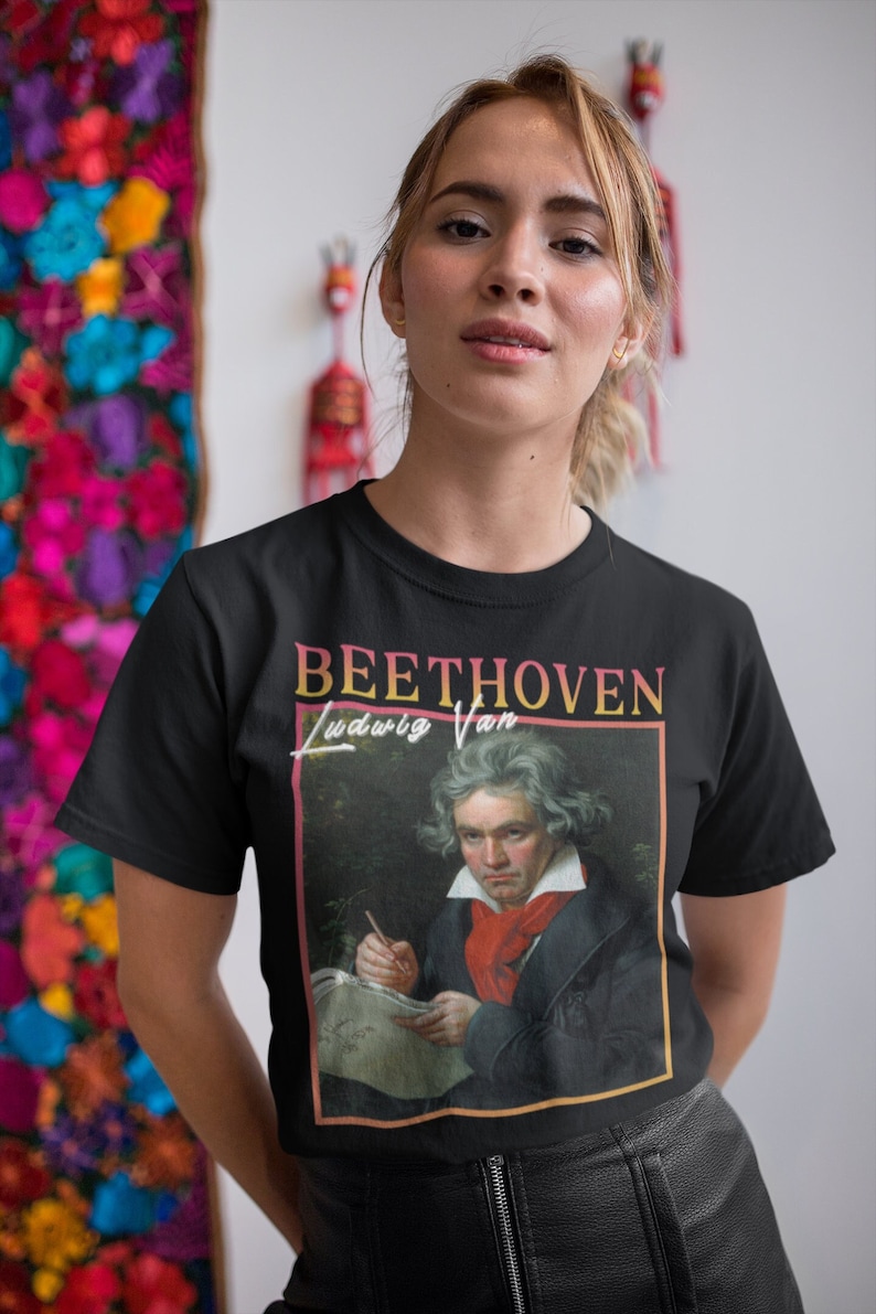 May include: A black t-shirt featuring a vintage-style graphic of Ludwig van Beethoven. The graphic includes a portrait of Beethoven and the text "BEETHOVEN Ludwig Van".