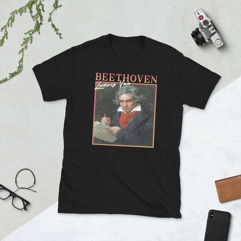 May include: Black t-shirt featuring a vintage-style graphic of Ludwig van Beethoven, with a portrait of the composer and the text "BEETHOVEN Ludwig Van" in a colourful, retro font.