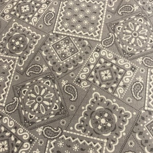 May include: A gray fabric with a white paisley pattern. The fabric is made up of repeating squares with different paisley designs.