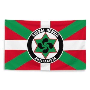 May include: A red, white, and green flag with a black circle in the center. The circle contains a green six-pointed star with a black Basque laburdun inside. The text "EUSKAL HERRIA ANTIFAXISTA" is written around the circle.