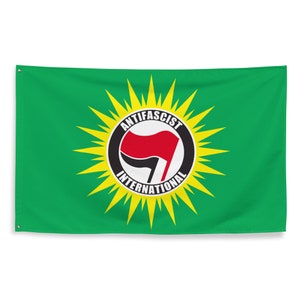 May include: Green flag featuring a central emblem with the text "ANTIFASCIST INTERNATIONAL" in a circular design. The emblem includes a red flag and a black circle, surrounded by yellow rays.