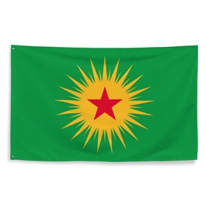 May include: Green flag with a central design of a red star inside a yellow sunburst. The flag has eyelets for hanging. The background is a solid, vibrant green.