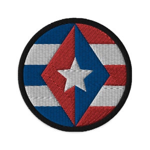 Puede incluir: Un parche redondo bordado con un diseño rojo, blanco y azul. El diseño presenta una estrella blanca en el centro de un diamante, rodeado de rayas rojas y azules.