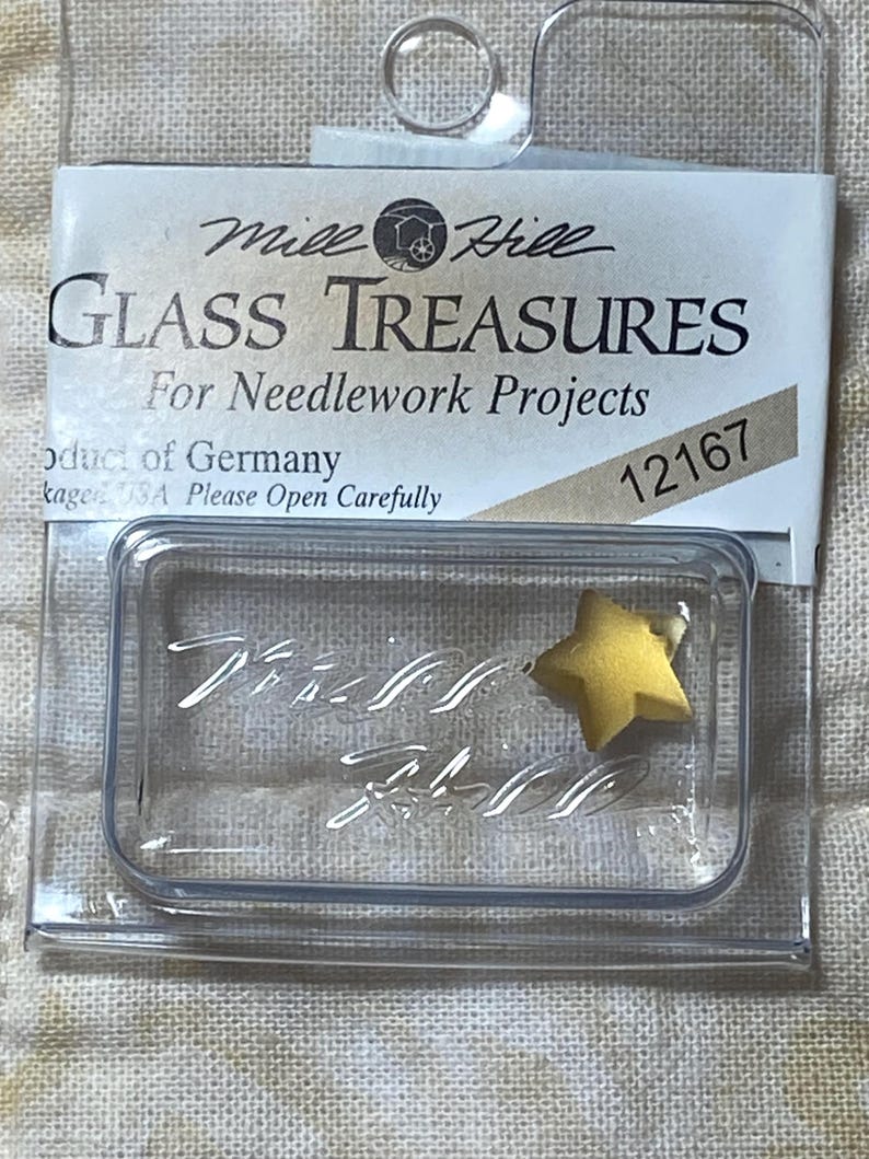 May include: A clear plastic package containing a yellow glass star. The package is labeled "Mile Hill Glass Treasures for Needlework Projects" and "12167".