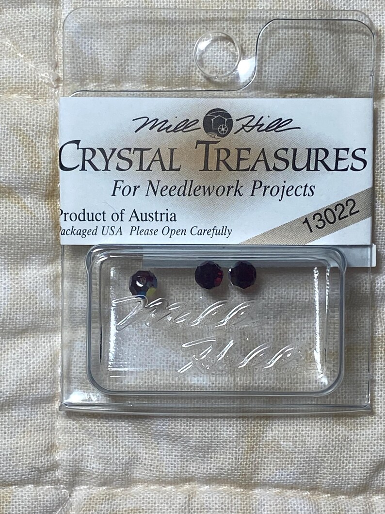 May include: A small plastic package containing three red crystal rhinestones for needlework projects. The package is labeled "Mile Hill Crystal Treasures" and "Product of Austria".
