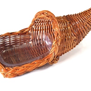 May include: A brown wicker cornucopia basket with a clear plastic liner. The basket is shaped like a horn and has a handle.