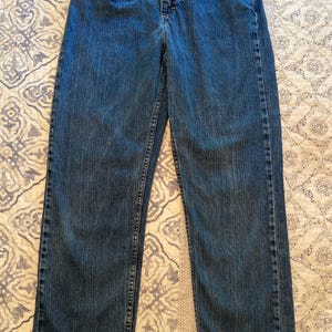 May include: A pair of medium-wash blue denim jeans featuring a classic five-pocket design, a button and zipper fly closure, belt loops, and visible topstitching along the seams. The jeans have a straight-leg cut and a standard waistband.