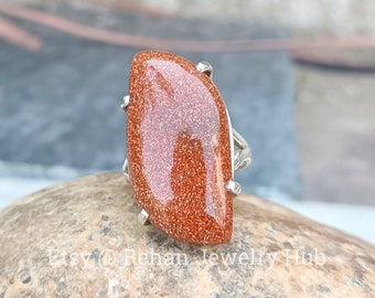 May include: A silver ring with a large, orange, faceted gemstone. The gemstone is set in a silver band with a delicate design.