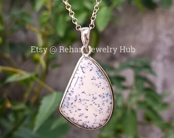 May include: A silver chain necklace with a white and black dendritic opal pendant. The pendant is a teardrop shape and has a silver bail.