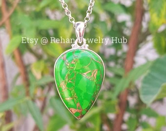 May include: A teardrop-shaped pendant with a green and gold gemstone set in sterling silver. The pendant is on a silver chain.