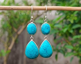 May include: A pair of silver dangle earrings with turquoise stones. The earrings have two stones on each, one round and one teardrop shaped.