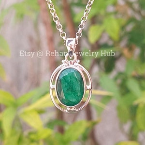 Peut inclure: Un collier avec un pendentif en argent orné d'une émeraude ovale verte sertie dans un cadre en argent. Le pendentif est suspendu à une chaîne en argent.