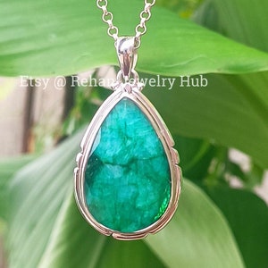 Peut inclure: Un collier avec un pendentif en émeraude en forme de larme et une chaîne en argent. L'émeraude est de couleur vert foncé et a une taille facetée. Le pendentif est serti dans un serti clos en argent.