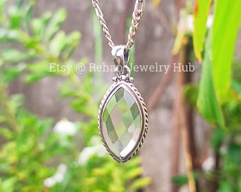 Può includere: Una collana color argento con un pendente di pietra preziosa verde chiaro sfaccettata. Il pendente è di forma ovale allungata, incorniciato da un bordo decorativo argentato. La catena è a maglie. Il testo "Etsy @ Rehan Jewelry Hub" è visibile.