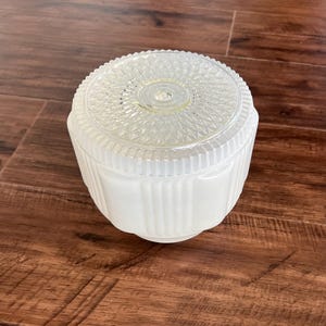 Peut inclure: Un abat-jour de luminaire rond en verre avec un dessus transparent texturé orné d'un motif en rayons de soleil et une base blanche opaque givrée avec des détails nervurés verticaux. L'abat-jour présente une ouverture circulaire au centre.