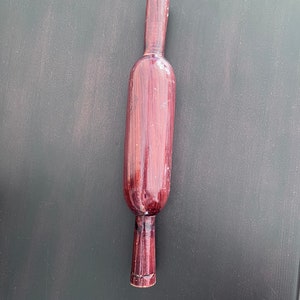 May include: A wooden rolling pin with a dark brown finish. The rolling pin is approximately 30 cm long and has a smooth, rounded surface.