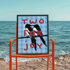 May include: A framed print with a blue and white checkered background. The print features two black and white birds perched on a branch with the words "TWO FOR JOY" written in red.