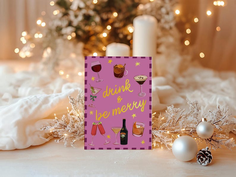 May include: A greeting card with a purple background and the words "drink & be merry" in gold script. The card features illustrations of various cocktails and a bottle of liquor. The background includes Christmas decorations and lights.