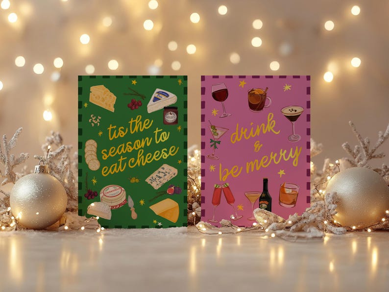 May include: Two festive greeting cards with holiday themes. One green card says "tis the season to eat cheese" with cheese illustrations. The other pink card says "drink & be merry" with drink illustrations. Decorative lights and ornaments surround the cards.