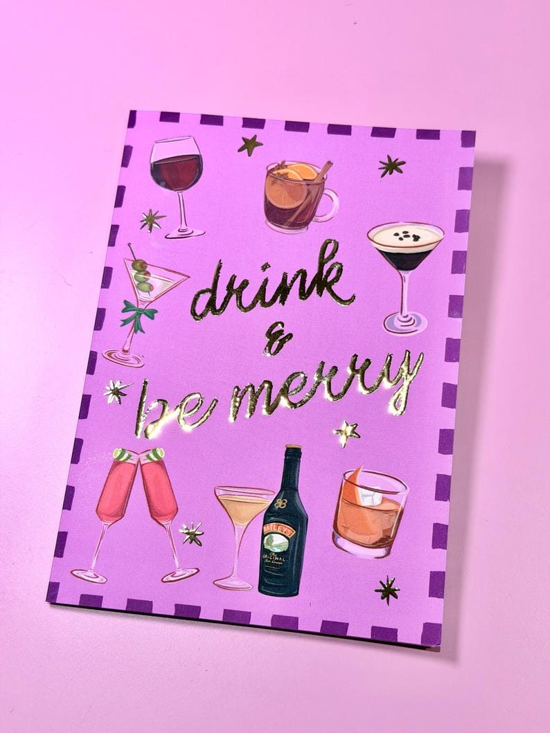 May include: A purple greeting card with gold lettering that reads "drink & be merry." The card features illustrations of various cocktails, including a martini, wine, and a bottle of Bailey's.