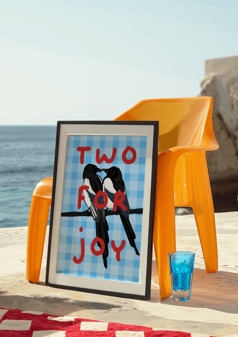May include: A framed print with a blue and white checkered background featuring two magpies perched on a branch. The text "TWO FOR JOY" is written in red on the print.