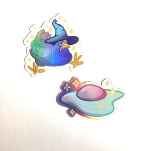 May include: Two colourful stickers featuring a cartoon chicken wearing a blue wizard hat and a blue and purple egg with gold sparkles.