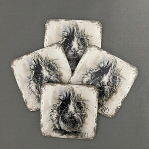 May include: Set of four coasters featuring black and white illustrations of guinea pigs with a distressed white background.