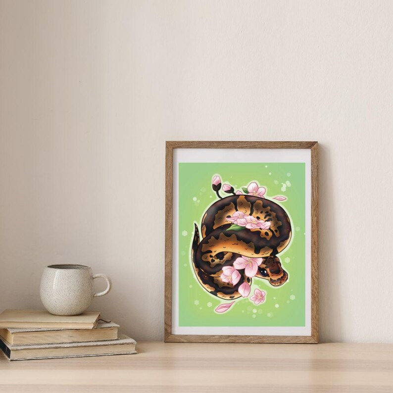 Peut inclure: Une impression encadr&eacute;e d'une illustration num&eacute;rique d'un serpent brun et noir avec des fleurs roses sur un fond vert.