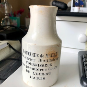 Puede incluir: Tarro de mostaza de cerámica blanca con letras negras que dicen "MOUTARDE de MAILLE Vinaigrier Distillateur FOURNISSEUR des premières Cours DE L'EUROPE PARIS".