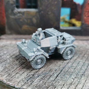Può includere: Un'auto blindata militare grigia in miniatura con una figura di un soldato sul sedile del conducente. L'auto ha quattro ruote e una capote in tela.